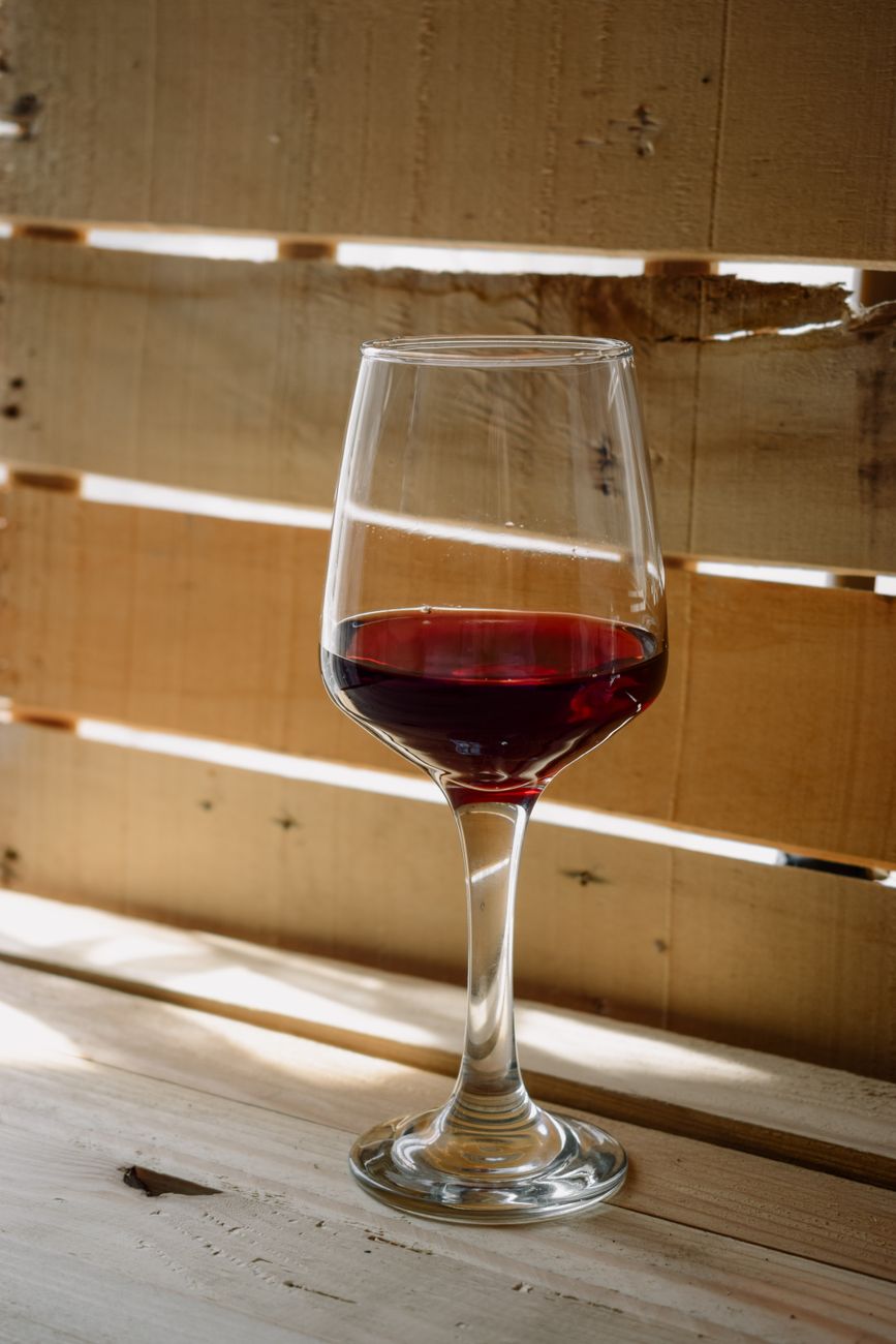 Close-up of a red wine glass on a rustic wood surface with natural lighting.
